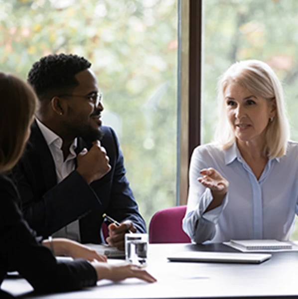 Senior woman leading a discussion with colleagues around a conference table