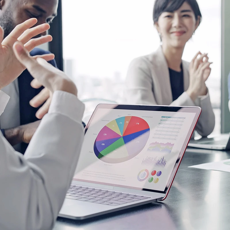 Business professionals reviewing financial charts and a colourful pie chart displayed on a laptop screen during a due diligence meeting