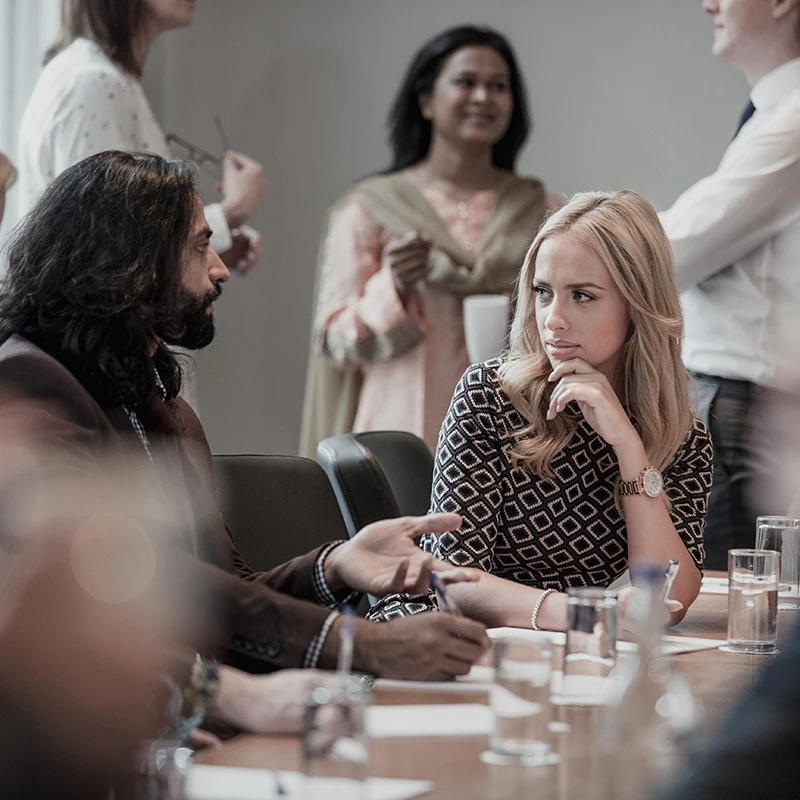 Colleagues discussing ideas during an inclusion workshop, seated at a conference table