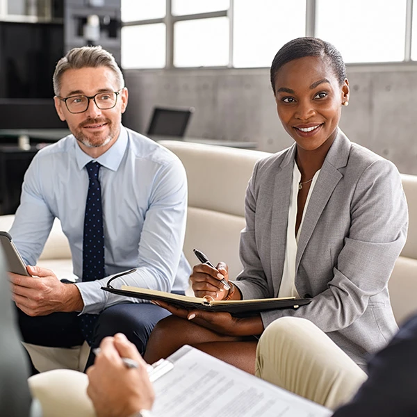 Businesswoman with a notebook and colleague listening and smiling during a leadership meeting